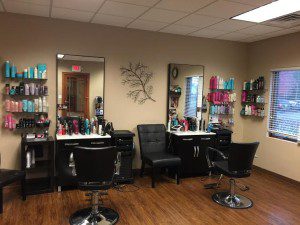 A salon with two black chairs and three mirrors