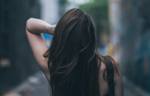 A woman with long hair is standing in the street.