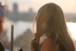 A woman with long blonde hair standing in front of a window.